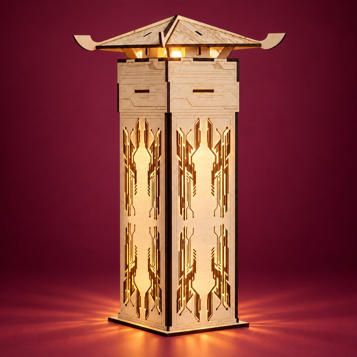 Faceted wooden lantern fully visible on a burgundy studio background, with warm golden light shining through its geometric cutouts
