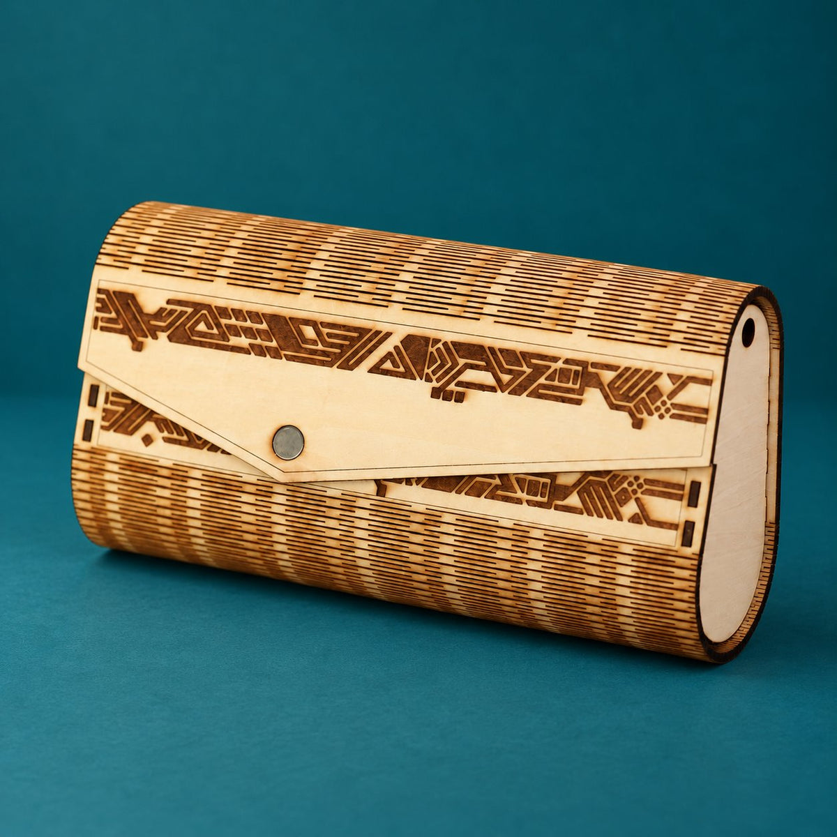 Geometric wooden clutch with engraved envelope flap, silver snap and curved cutwork shell on a deep teal background.